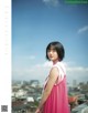 A woman in a pink dress standing on top of a building.